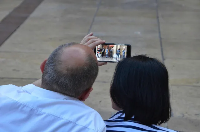 couple, watch, cellphone, together, entertainment, video, camera, outdoors, taking video, park, mobile phone. Designing captions that remain readable on a phone