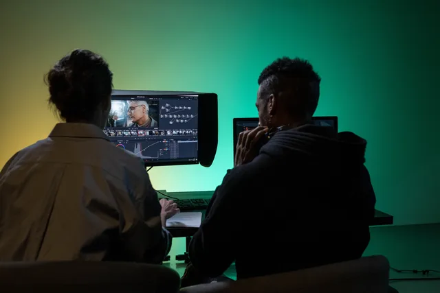 Two professionals collaborate on video editing with color grading software. Managing recurring UGC production